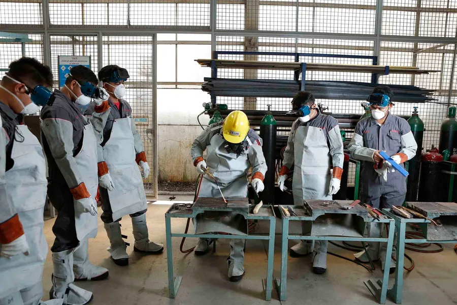 Equipe de operários de capacete ouvindo uma orientação em ambiente industrial