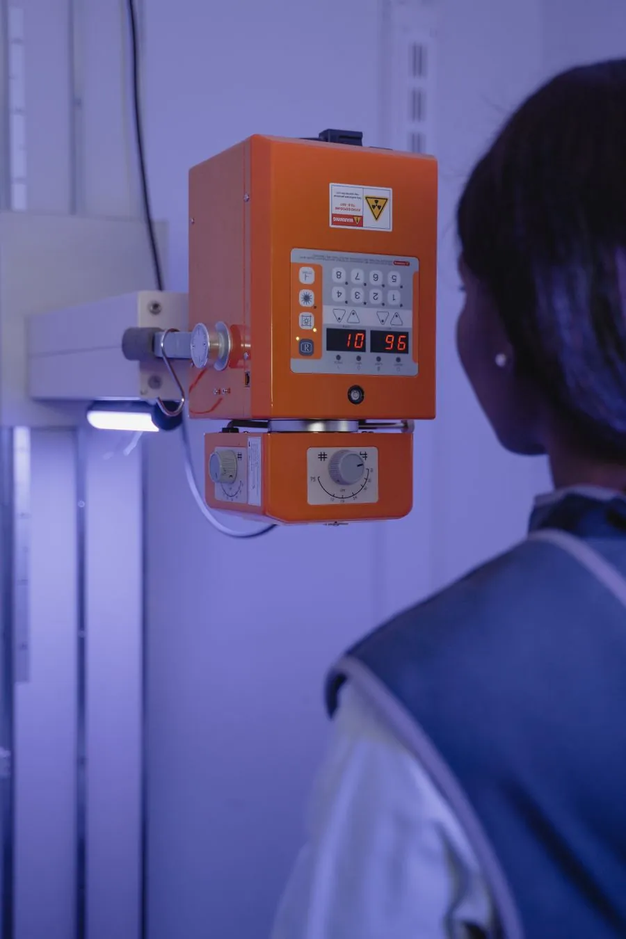 Mãos ajustando botões e painel de controle de um equipamento de raio-x