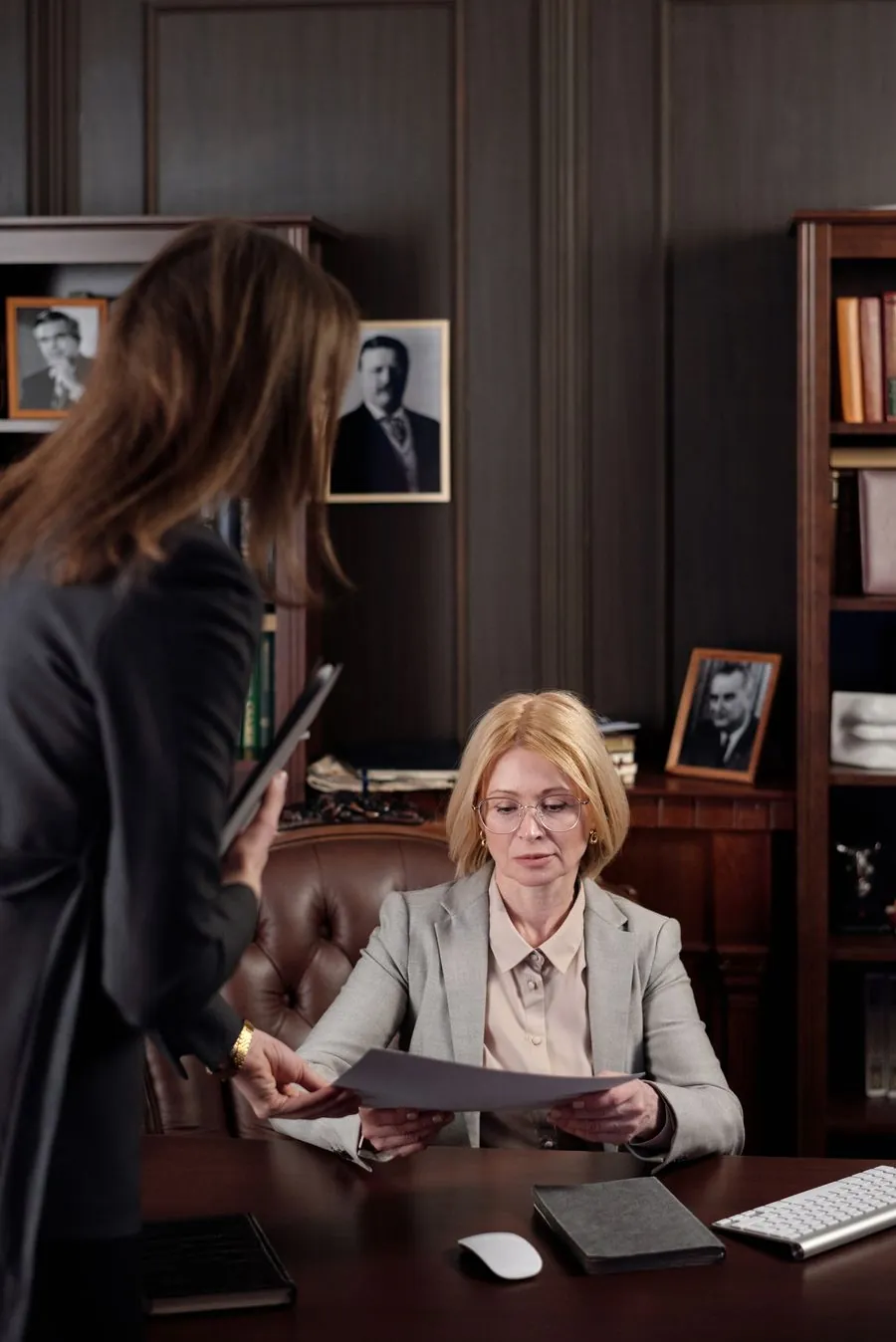 Atendimento presencial a um responsável sentado em frente à mesa da secretaria